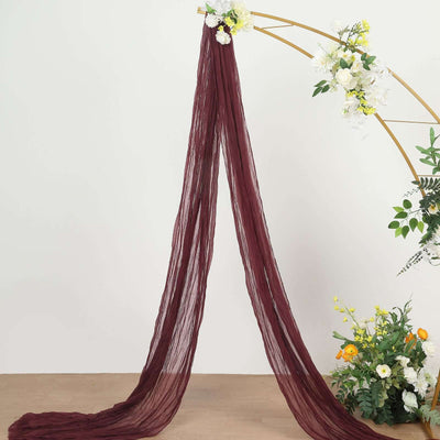Burgundy sheer fabric draping elegantly on a floral arch