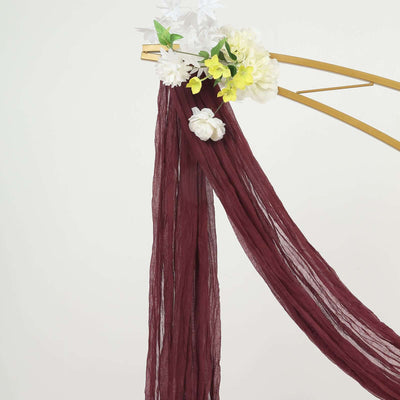 Burgundy draped fabric with white and yellow floral accents
