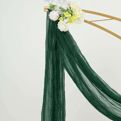 Green sheer fabric draped elegantly with floral accents on a gold stand.