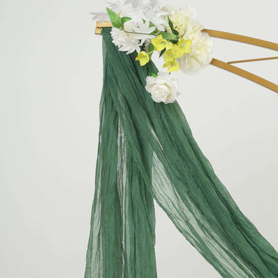 Green sheer scarf draped with artificial flowers on a gold hanger