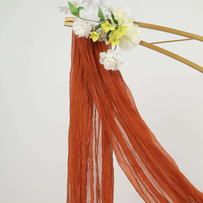 Rust-colored chiffon drapery with floral accents on a gold frame