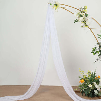 White sheer fabric draped elegantly on a floral arch.