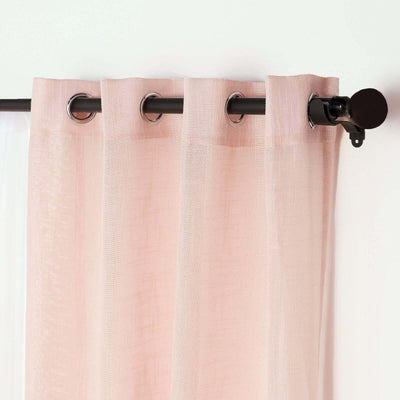 Light pink sheer curtain with metal grommets on a black rod.