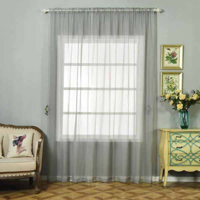 Sheer gray curtain hanging in a room with vintage furniture and decor.