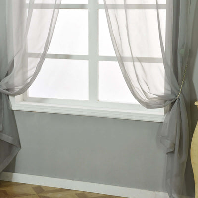 Sheer gray curtains hanging by a window in a softly lit room.