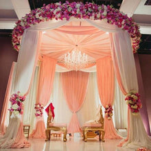 White sheer organza ceiling drapes on a wedding stage decorated with flowers and a chandelier