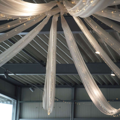 Draped sheer fabric with fairy lights in a decorative ceiling installation.