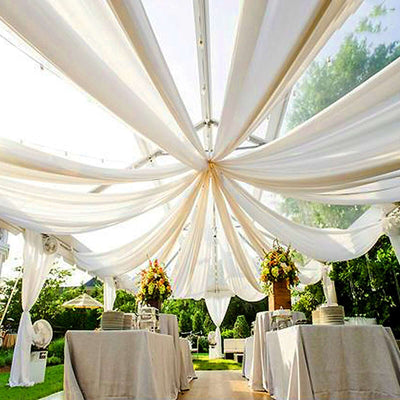 Elegant outdoor event setup with draped fabric and floral centerpieces.