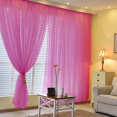 Pink sheer curtains in a cozy living room with a lamp and furniture.