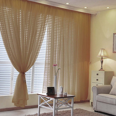 Elegant sheer yellow curtains in a cozy living room setting with a sofa and lamp.
