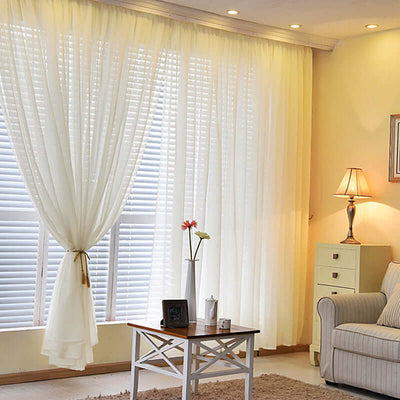 Sheer white curtains elegantly draping a window in a cozy living room setting.