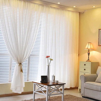 Sheer white curtains elegantly framing a sunny living room with cozy decor.