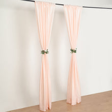 A pair of blush polyester curtains hanging on a black pole