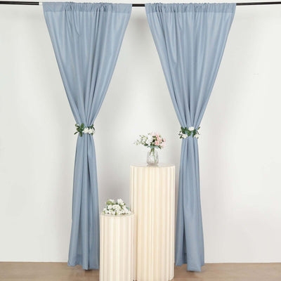 Blue curtains with floral ties, elegantly draped on a plain backdrop.