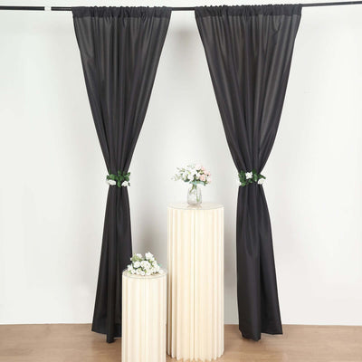Black sheer curtains styled with floral accents on elegant pedestals.