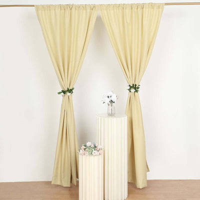 Beige curtains with floral ties and decorative pedestals in a studio setting.