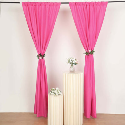 Pink curtains with floral accents displayed on white pedestals.