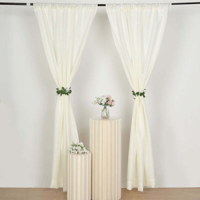 Elegant cream curtains with floral accents in a studio setting.
