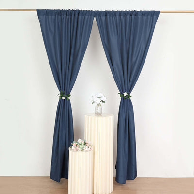 Navy blue curtains draped elegantly around a vase of flowers on a pedestal table.