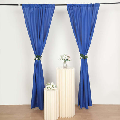 Blue curtains with floral accents and decorative pedestals in a staged setting.