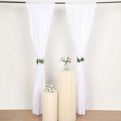 White curtains with floral accents and decorative pedestals in a staged setting.