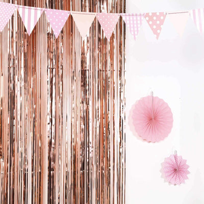 Pink party decorations with bunting and paper fans against a shiny backdrop.