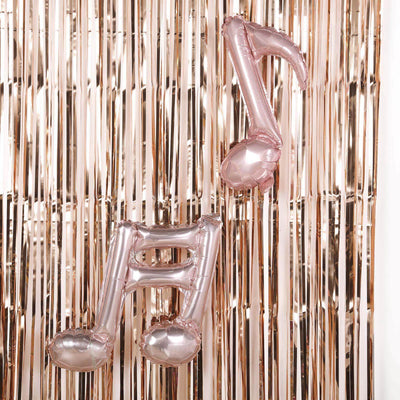 Rose gold musical note balloon against a shiny backdrop.