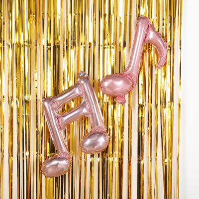 Rose gold musical note balloons against a shiny gold backdrop.