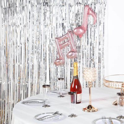 Pink musical note balloons above a festive table setting with champagne and elegant tableware.