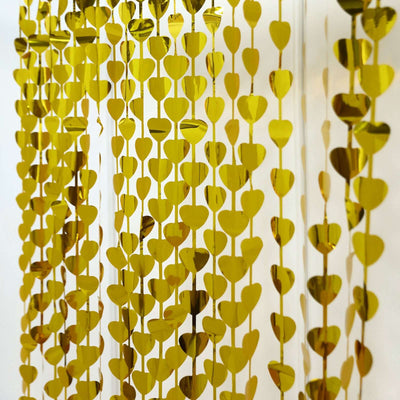Gold heart-shaped garland decoration hanging on a white background.