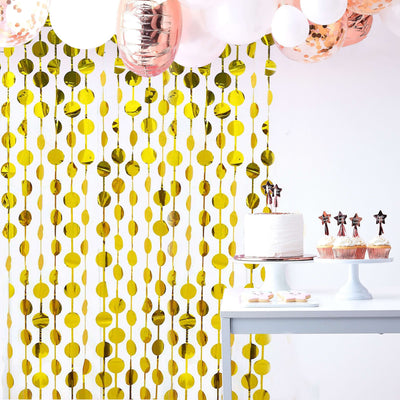 Gold circle party backdrop with balloons and a dessert table for celebrations.