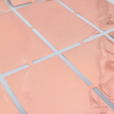 Rose gold foil square grid pattern on a smooth surface.