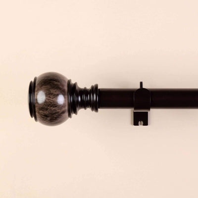 Black curtain rod with decorative finial on a beige background.