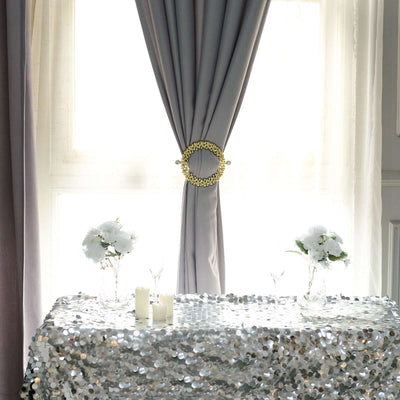 Elegant table setting with sequined tablecloth and floral arrangements in clear vases.