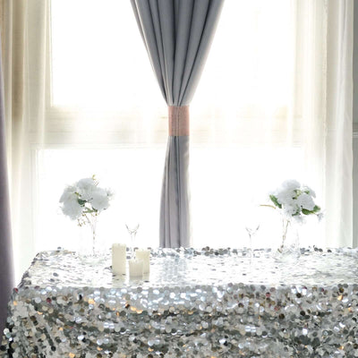 Elegant table setting with silver sequin tablecloth and floral arrangements.