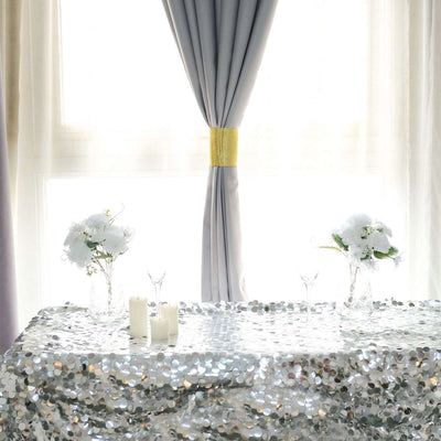 Elegant table setting with floral arrangements and candles, adorned with a sequined tablecloth.