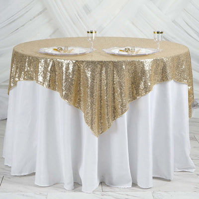 Gold sequin tablecloth draped over a round table with elegant dining setup.