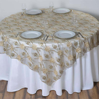 Round table with gold floral tablecloth, white plates, and wine glasses.