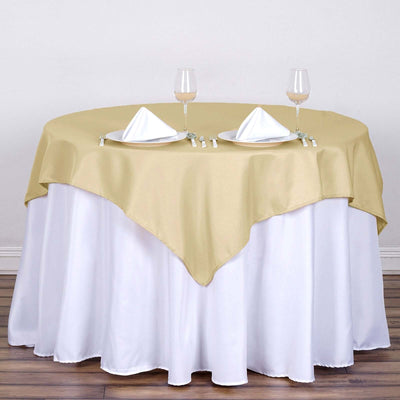 Gold tablecloth draped over a round table set for two with elegant glassware.