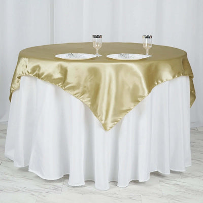 Elegant round table with gold satin tablecloth and two glasses
