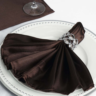 Elegant brown satin napkin with jeweled ring on a decorative plate.