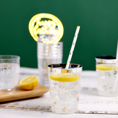 Sparkling water with lemon slice in clear glass on a rustic wooden table.
