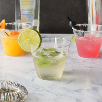 Refreshing cocktails with lime garnish on a marble countertop.