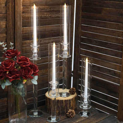 Elegant glass candle holders with white candles and decorative flowers.