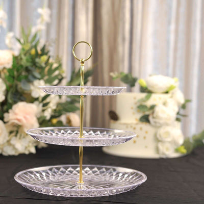 Three-tiered crystal cake stand with gold accents, elegantly displayed.