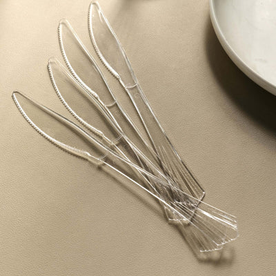 Clear plastic knives arranged neatly on a table.