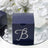 Navy blue gift box with rhinestone letter "B" design on mirrored surface.