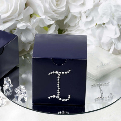 Navy gift box decorated with rhinestones on a reflective surface.