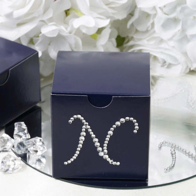Navy blue gift box with pearl embellishments on a mirrored surface
