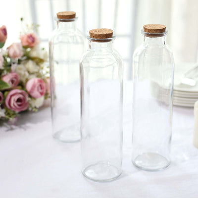 Clear glass bottles with cork lids on a table.